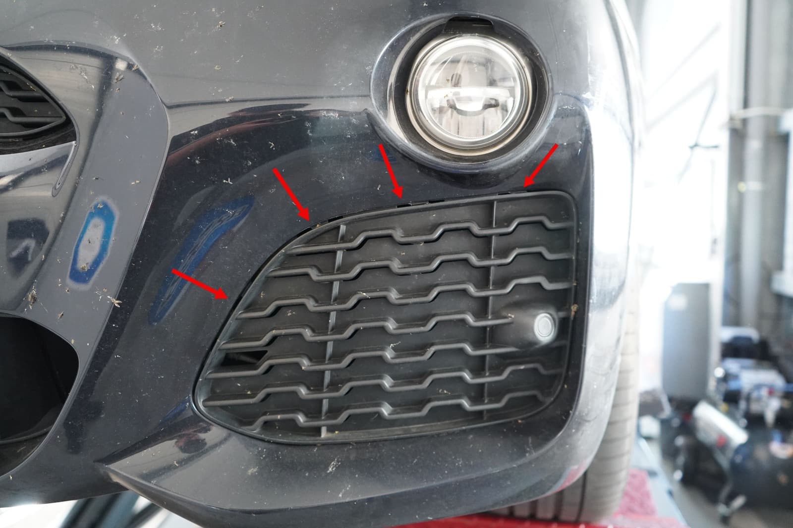 Detailbild markierter Spuren am Frontgitter eines schwarzen BMW X3 bei der Schadenprufung.