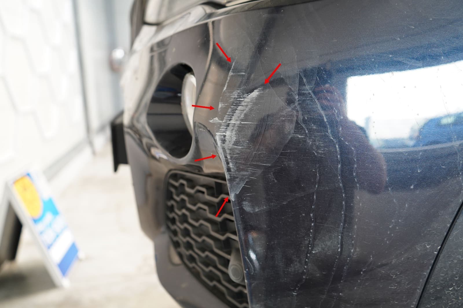 Detailaufnahme von Schadenspuren am vorderen Karosseriebereich eines schwarzen BMW X3.