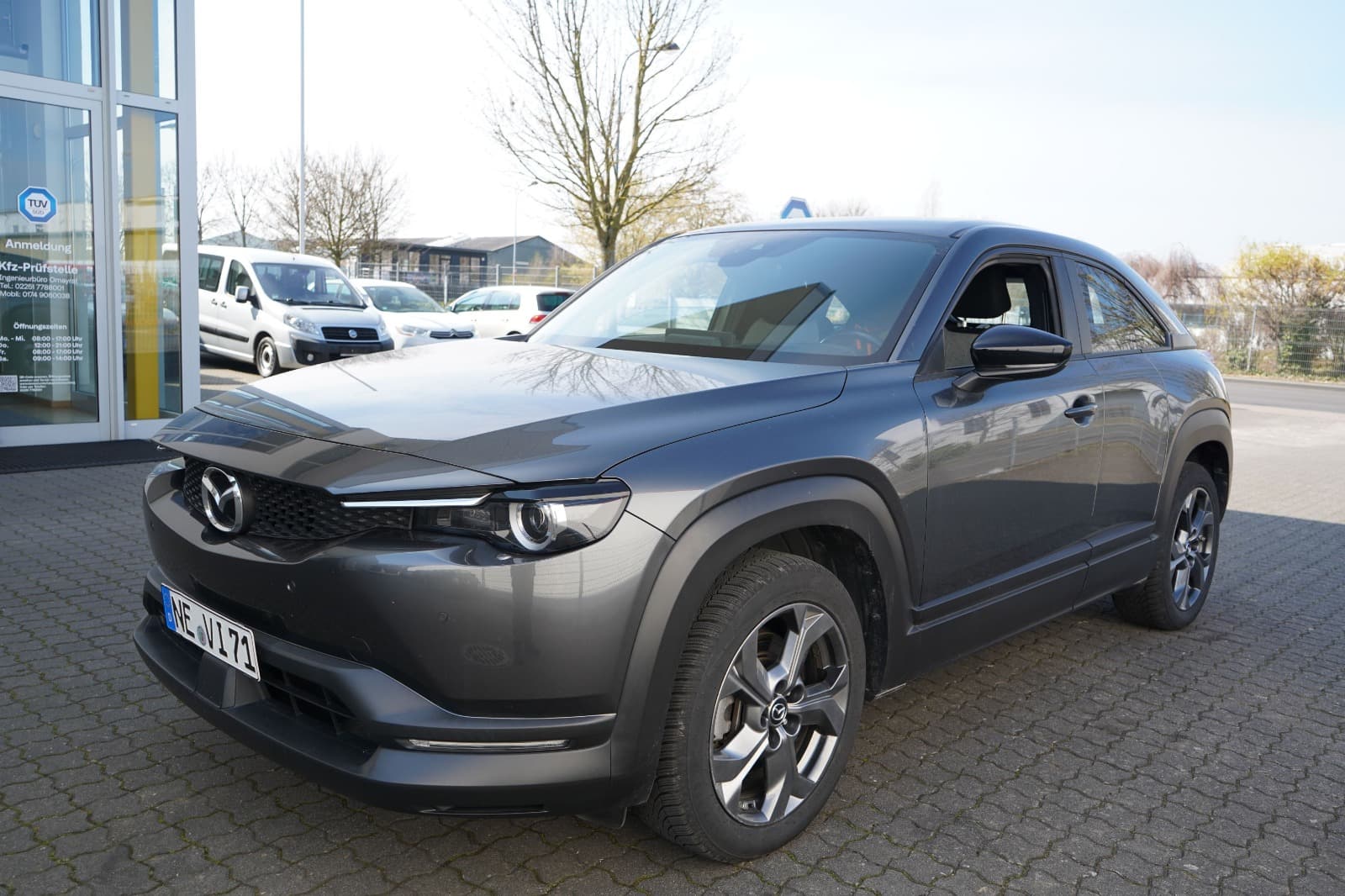 Front- und Seitenansicht eines grauen Mazda MX-30 bei der Begutachtung durch einen Kfz-Gutachter.