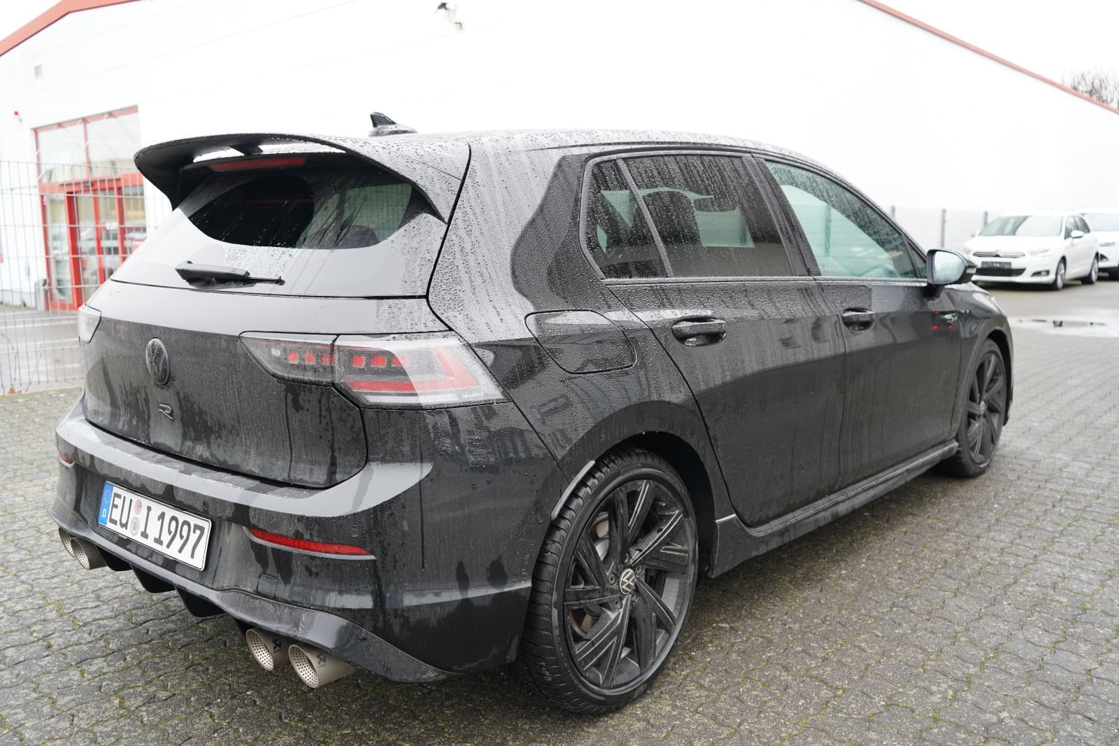 Heck- und Seitenansicht eines schwarzen VW Golf bei der Schadenaufnahme durch einen Gutachter.