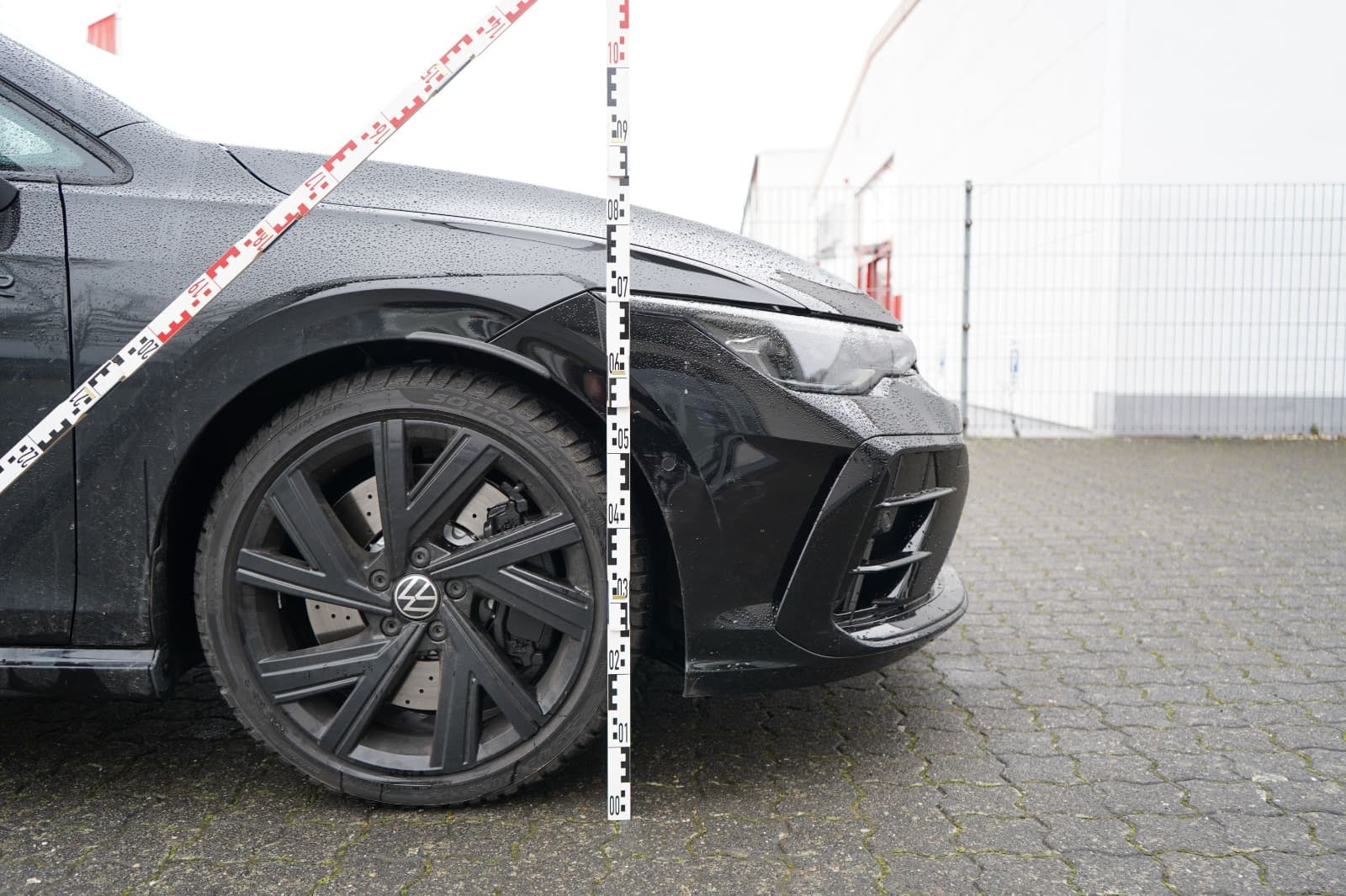 Seitenansicht eines schwarzen VW Golf mit Messskala bei der professionellen Schadenaufnahme.