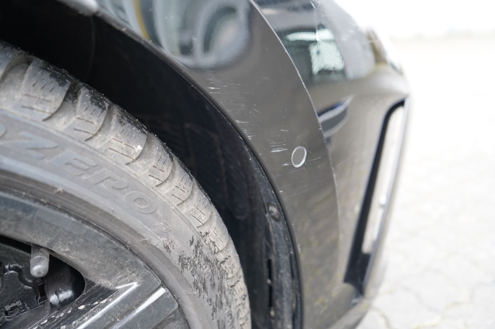 Detailbild eines markierten Schadens am Radlauf und Reifenbereich eines VW Golf.