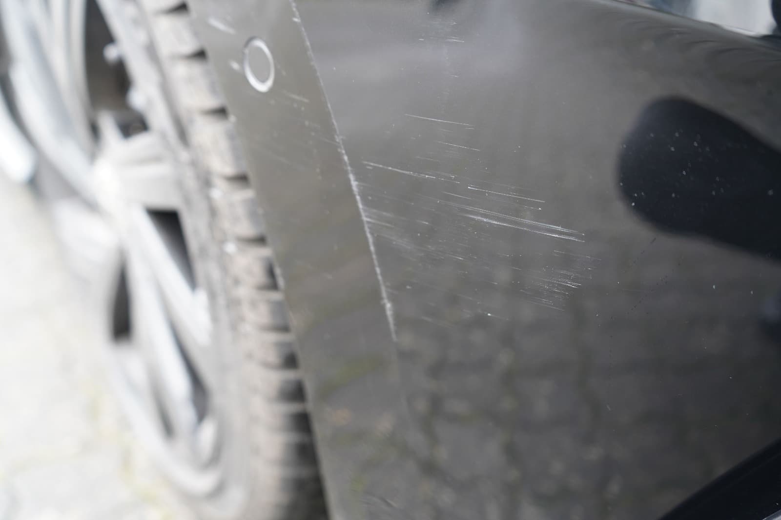 Nahaufnahme von Kratzern am schwarzen VW Golf zur Beweissicherung durch einen Gutachter.