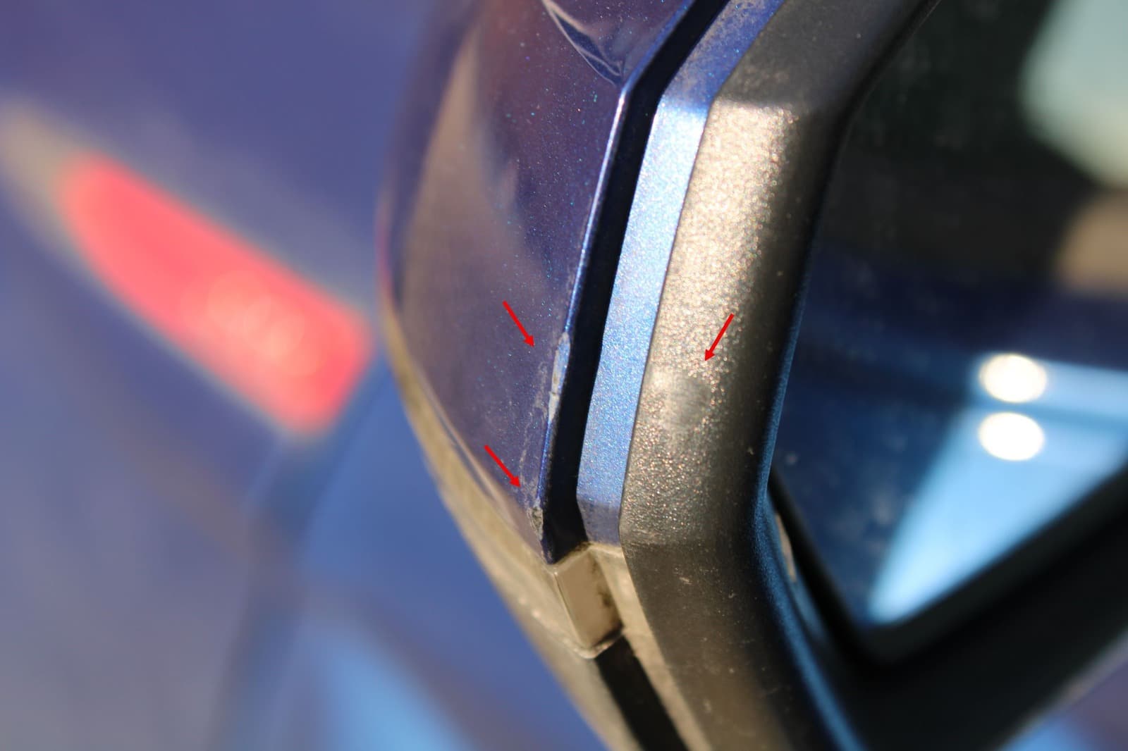 Nahaufnahme markierter Kratzer am Spiegelbereich eines blauen VW Polo.