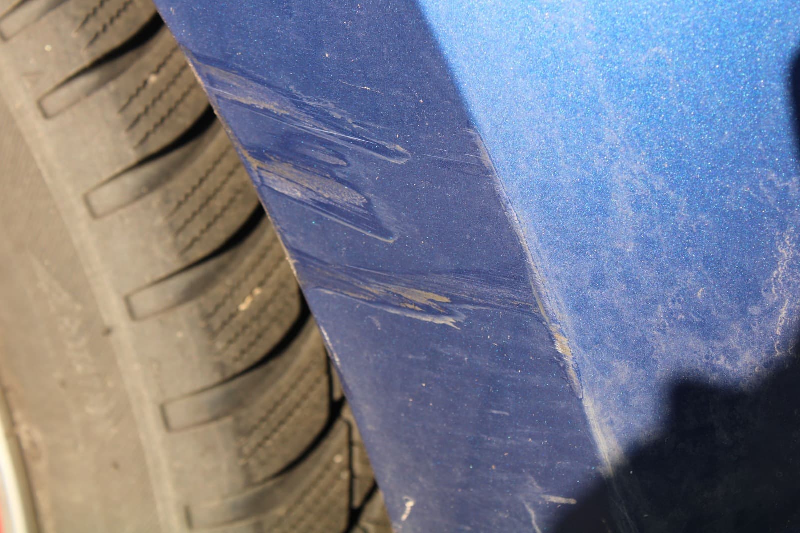 Detailaufnahme markierter Lackspuren am Radlauf eines blauen VW Polo.