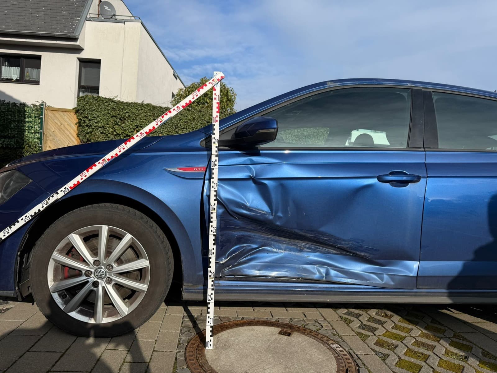 Seitenansicht des blauen VW Polo mit Messlatte fur ein Kfz-Gutachten in NRW.