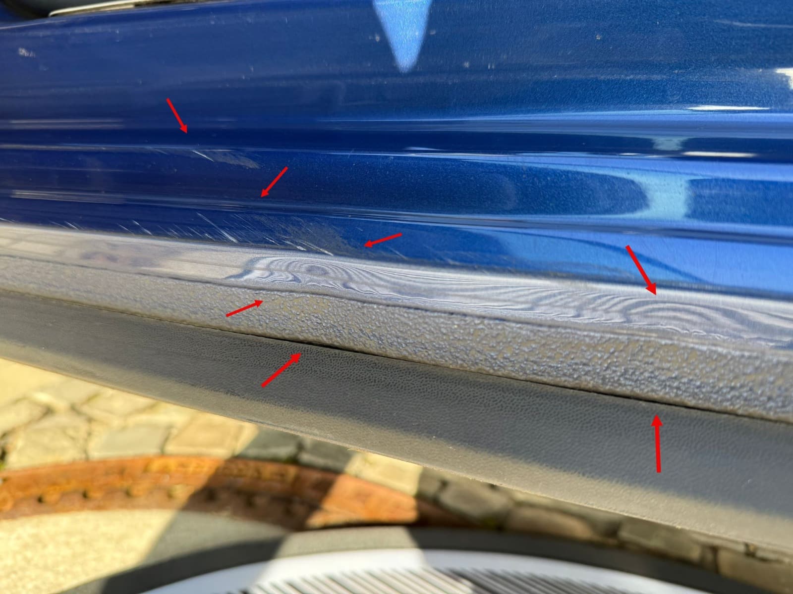 Nahaufnahme von Lack- und Kratzspuren am Schweller eines blauen VW Polo.