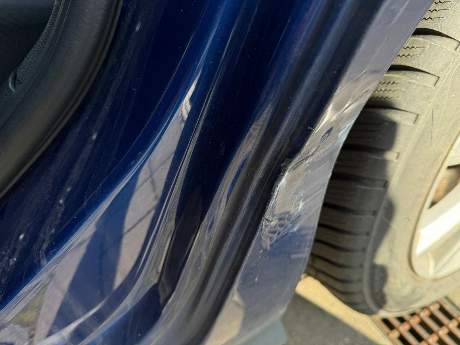 Nahaufnahme eines markierten Schadens am Radlauf und Seitenbereich eines blauen VW Polo.