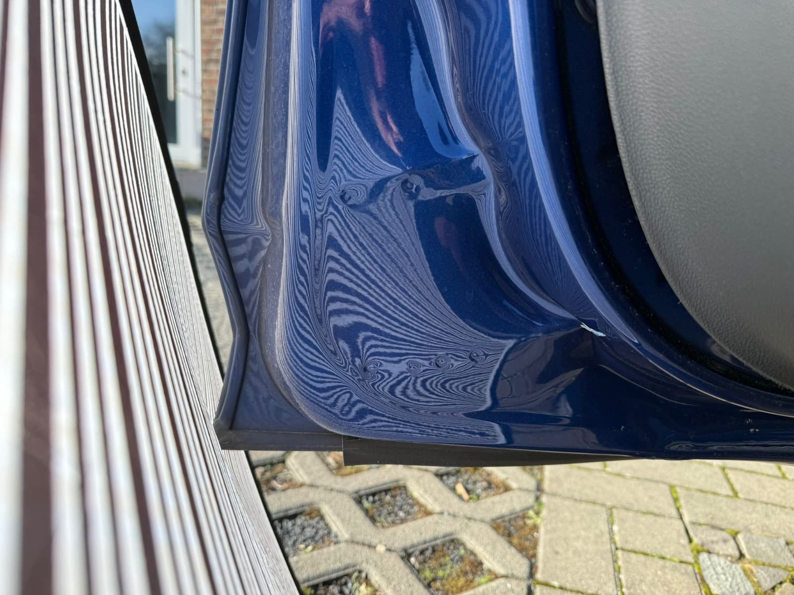 Detailbild von Kratzspuren am unteren Schweller eines blauen VW Polo.