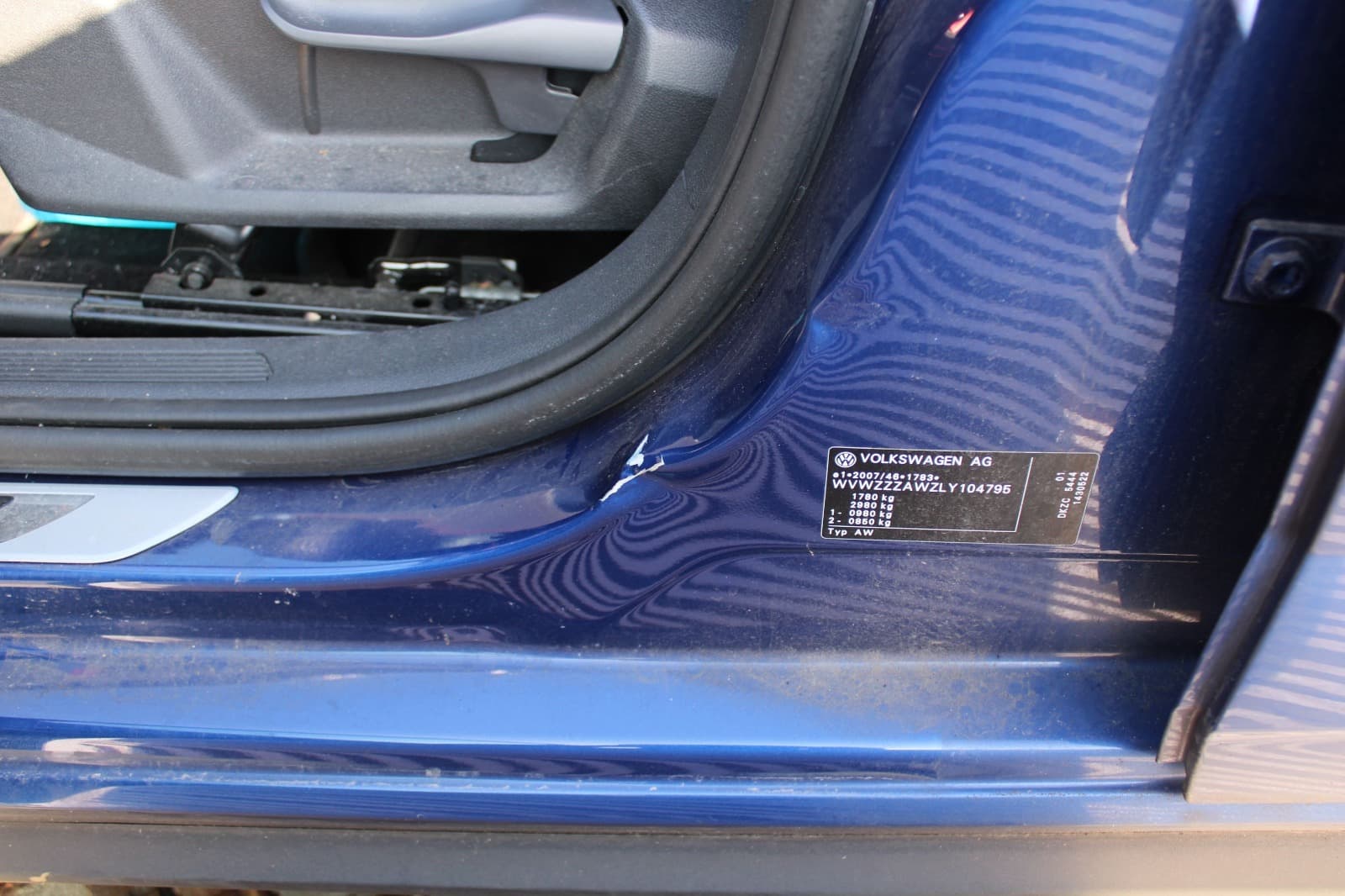 Nahaufnahme eines markierten Lackschadens am Tureinstieg eines VW Polo.