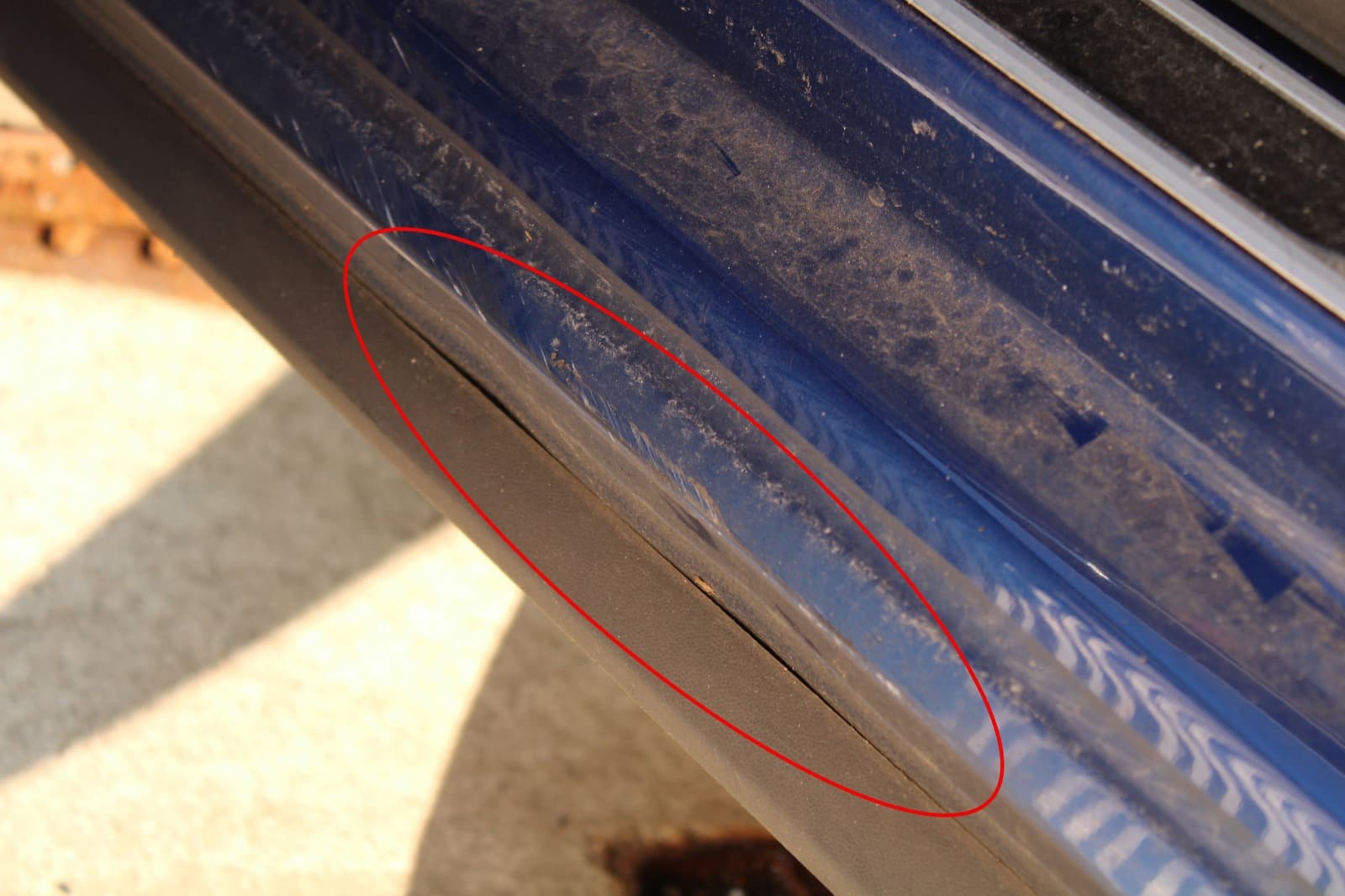 Nahaufnahme eines markierten Kratzers am Schweller eines blauen VW Polo fur ein Kfz-Gutachten.